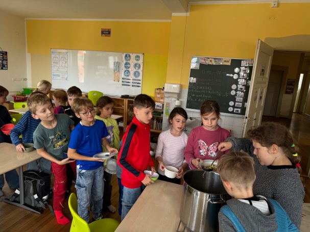Erntedankessen Schüler stehen in einer Reihe und bekommen Essen aus einem großen Topf.