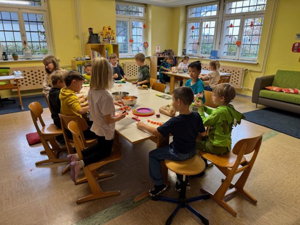 Erntedankessen Kinder sitzen an einem Tisch und arbeiten an Bastelprojekten in einem hellen Raum.