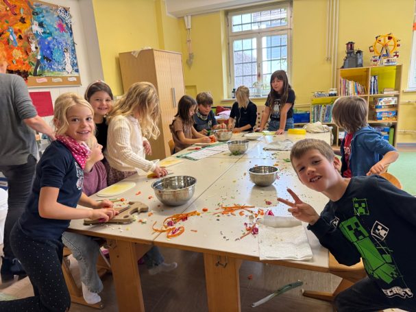 Erntedankessen Kinder arbeiten gemeinsam an einem Tisch, basteln mit buntem Material und haben Spaß.