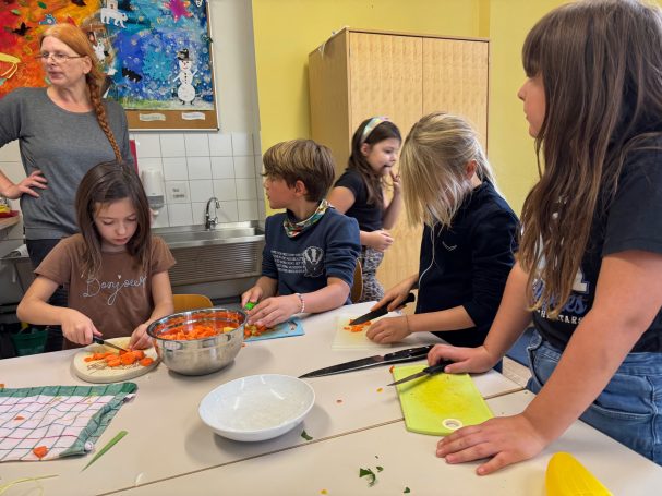 Erntedankessen Eine Gruppe von Kindern kocht gemeinsam in einer Küche und schneidet Gemüse.