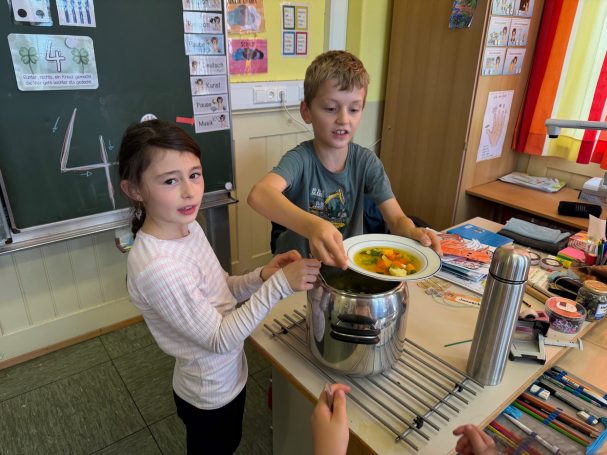 Erntedankessen Zwei Kinder stehen an einem Tisch und bereiten gemeinsam eine Schüssel mit Gemüse vor.